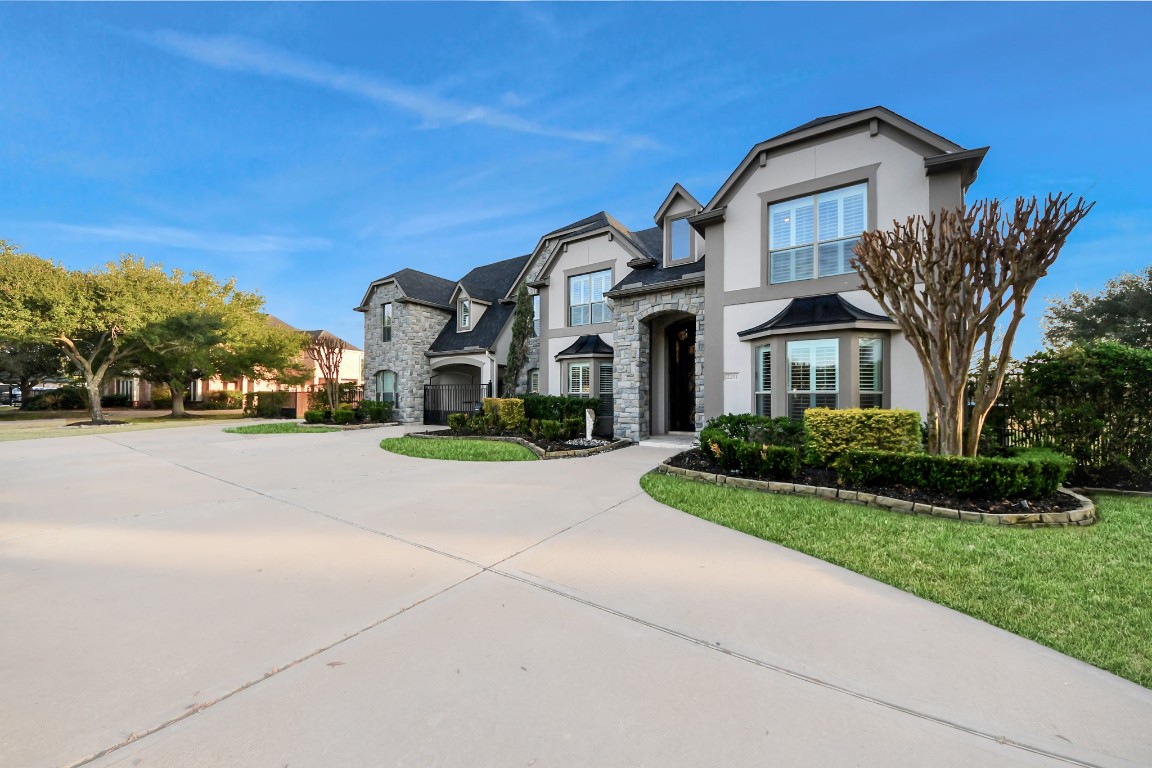 2211 Braer Ridge Drive Katy, TX 77494 - Photo 5 of 50 This elegant two-story home features a stone and stucco exterior with a grand entryway. It includes a spacious driveway, well-maintained landscaping, and a charming mix of traditional and modern architectural elements, offering great curb appeal in a suburban setting.