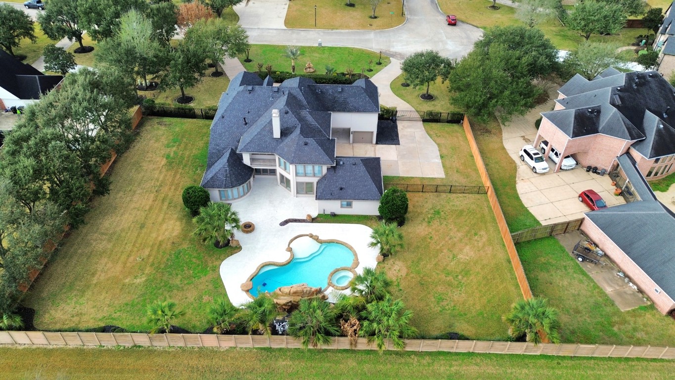 2211 Braer Ridge Drive Katy, TX 77494 - Photo 8 of 50 This property features a spacious two-story home with a large backyard, beautifully landscaped with mature trees. It includes a stunning, uniquely shaped pool with a spa, surrounded by a privacy fence. The driveway offers ample parking space, and the neighborhood appears quiet and well-maintained.