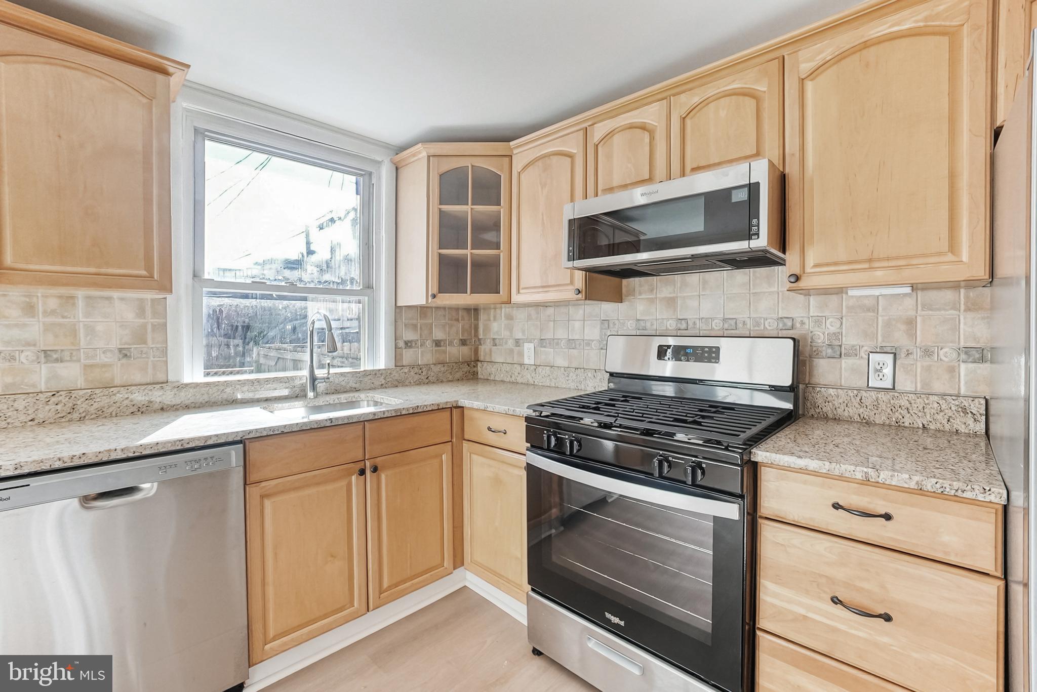 2725 Hudson Street Baltimore, MD 21224 - Photo 27 of 66 a kitchen with granite countertop white cabinets a window and a stainless steel appliances