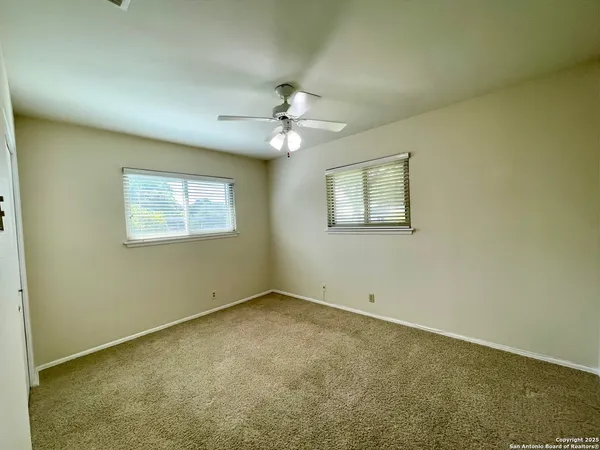 an empty room with windows and fan