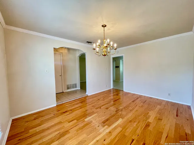 a view of a big room with wooden floor and chandelier