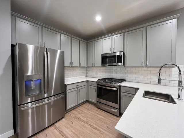 a kitchen with stainless steel appliances granite countertop a refrigerator stove and sink