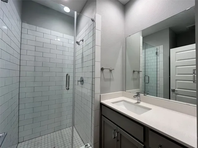 a bathroom with a sink shower and a mirror