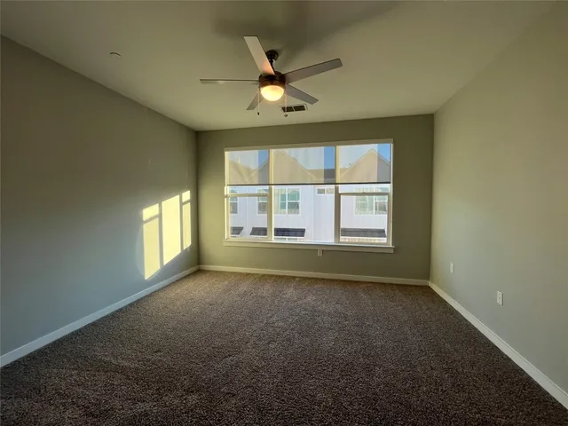 an empty room with chandelier fan and windows