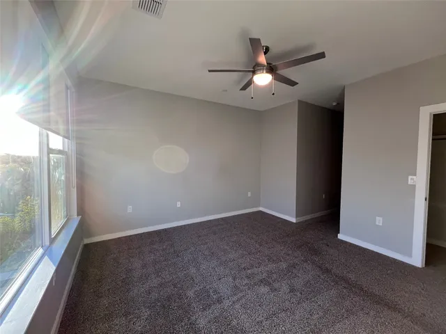 an empty room with windows and fan