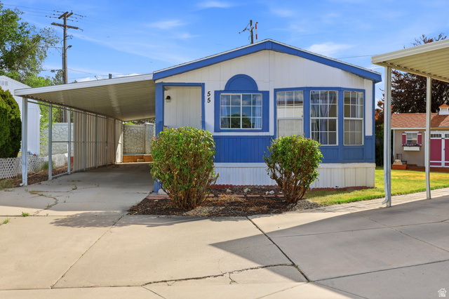 Single-story residence featuring a blue and white exterior, multiple windows, and a covered carport