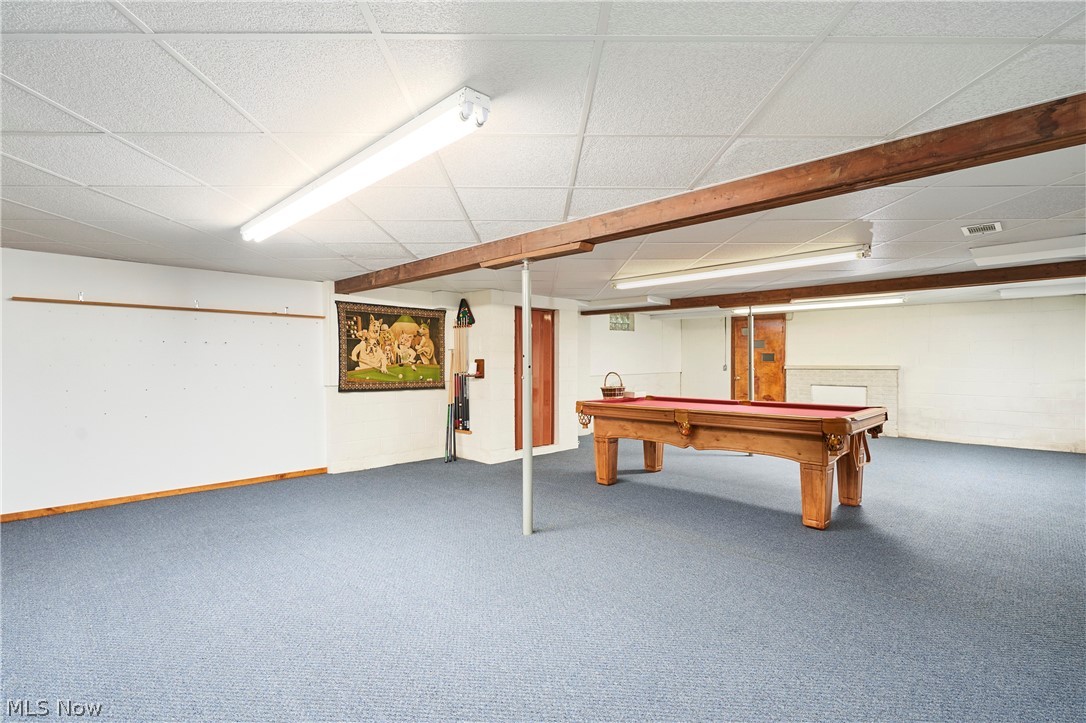 299 West Caston Road New Franklin, OH 44319 - Photo 19 of 23 Spacious lower-level room featuring blue carpeting, exposed wood beams, and a drop ceiling with fluorescent lighting