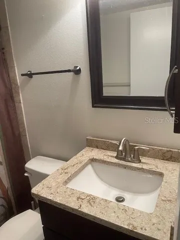 a bathroom with a granite countertop sink and a toilet