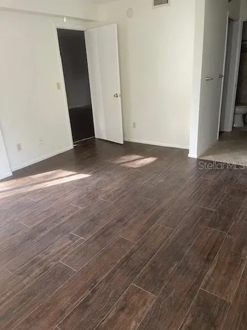 an empty room with wooden floor and entrance