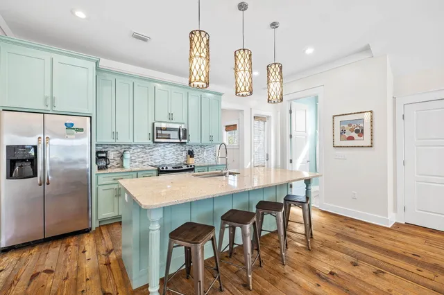a kitchen with stainless steel appliances a dining table chairs and wooden floor