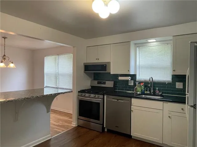 a kitchen with granite countertop a sink a stove and cabinets