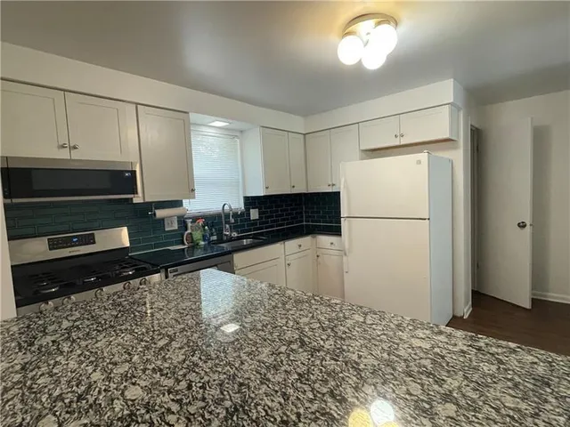 a kitchen with granite countertop a refrigerator and a stove top oven