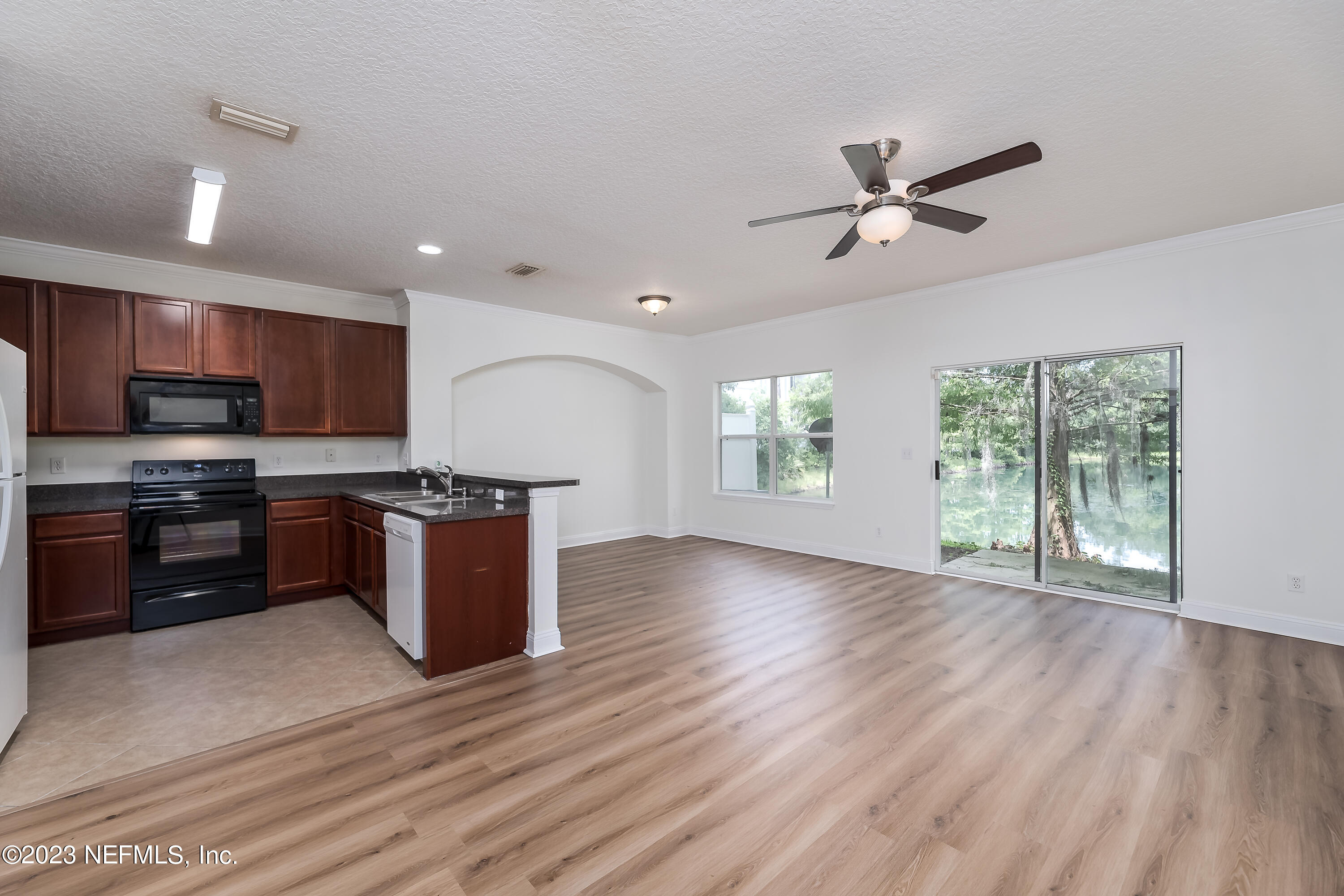 5260 Collins Road, Unit 1102 Jacksonville, FL 32244 - Photo 1 of 23 a kitchen with stainless steel appliances granite countertop a stove top oven a sink with wooden floors and white cabinets