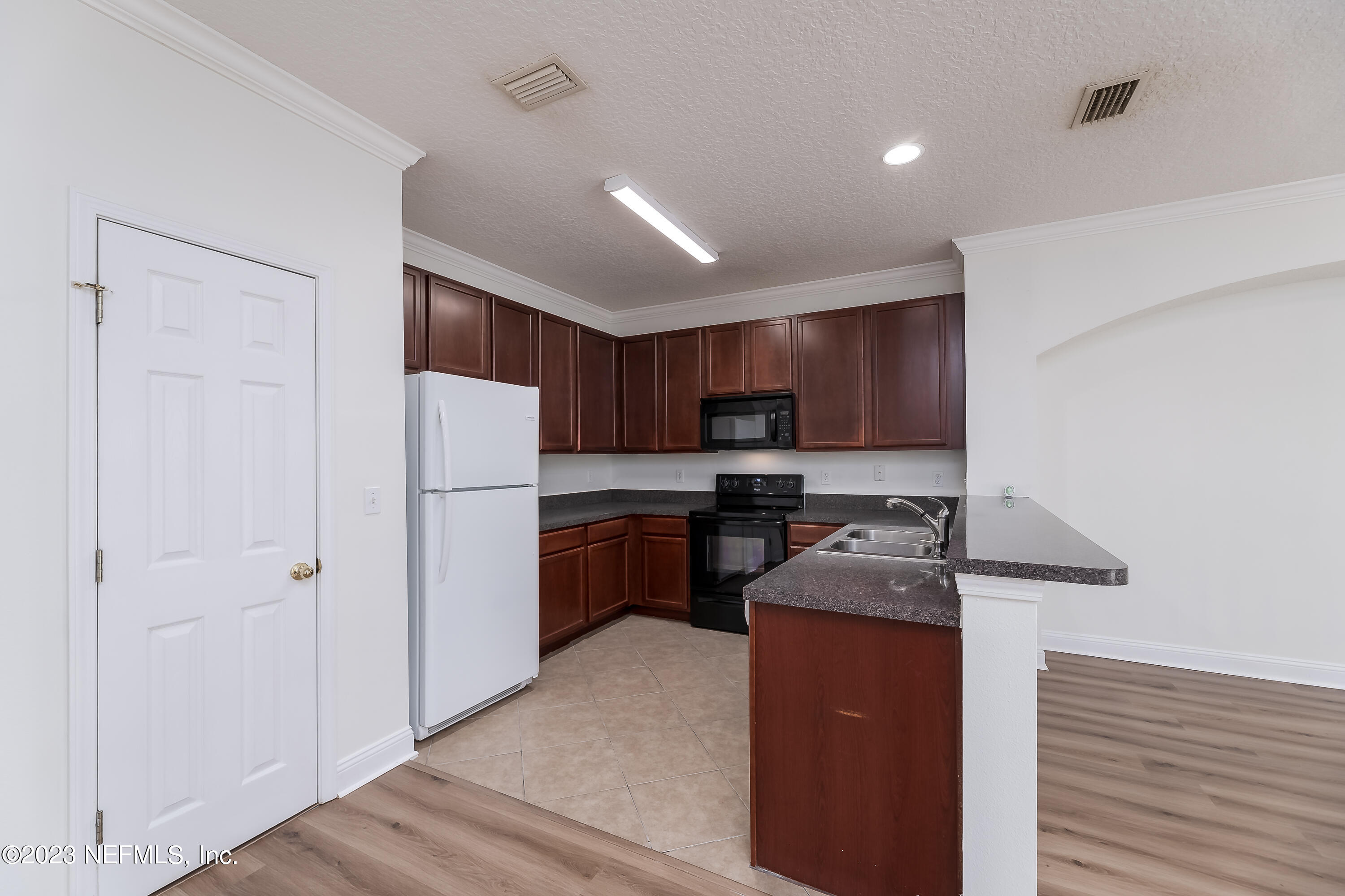 5260 Collins Road, Unit 1102 Jacksonville, FL 32244 - Photo 7 of 23 a kitchen with refrigerator a stove a sink and cabinets