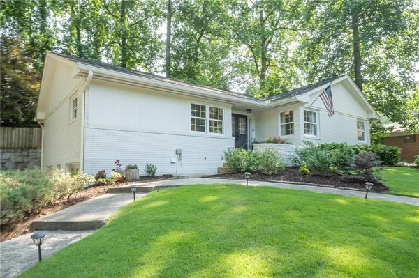 a backyard of a house with plants and large tree