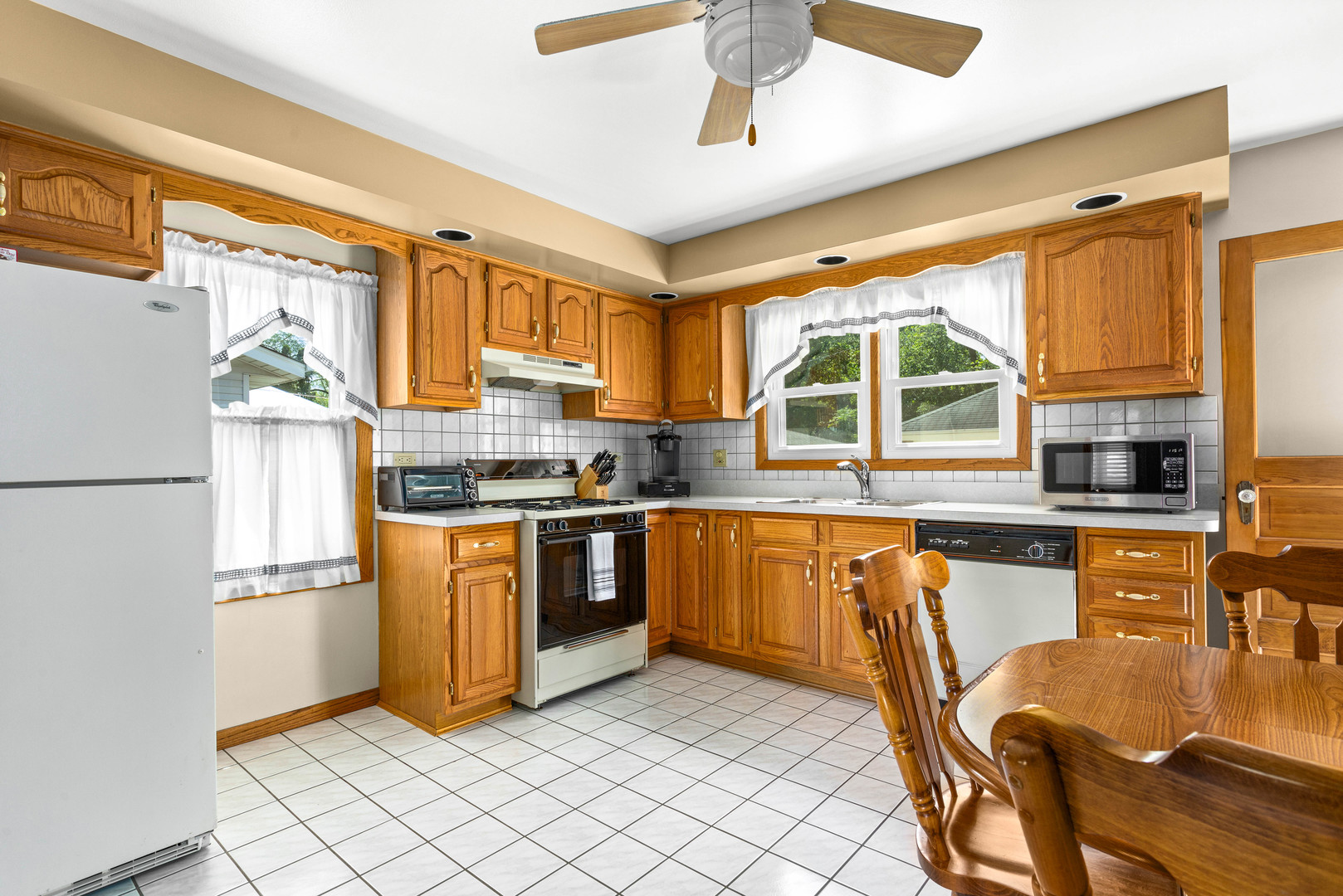 11133 Revere Road Mokena, IL 60448 - Photo 12 of 22 a kitchen with a refrigerator a stove a sink dishwasher a dining table and chairs with wooden floor