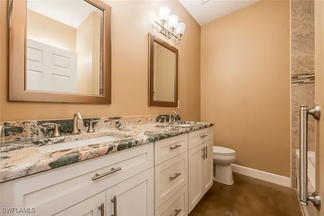 a bathroom with a granite countertop toilet sink and mirror
