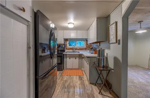 a kitchen view with stainless steel appliances a refrigerator and a wooden floor