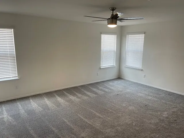 an empty room with windows and fan
