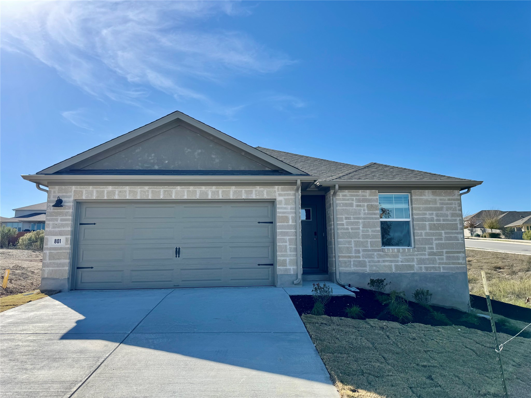 Ranch-style home featuring stone siding, driveway, and a garage