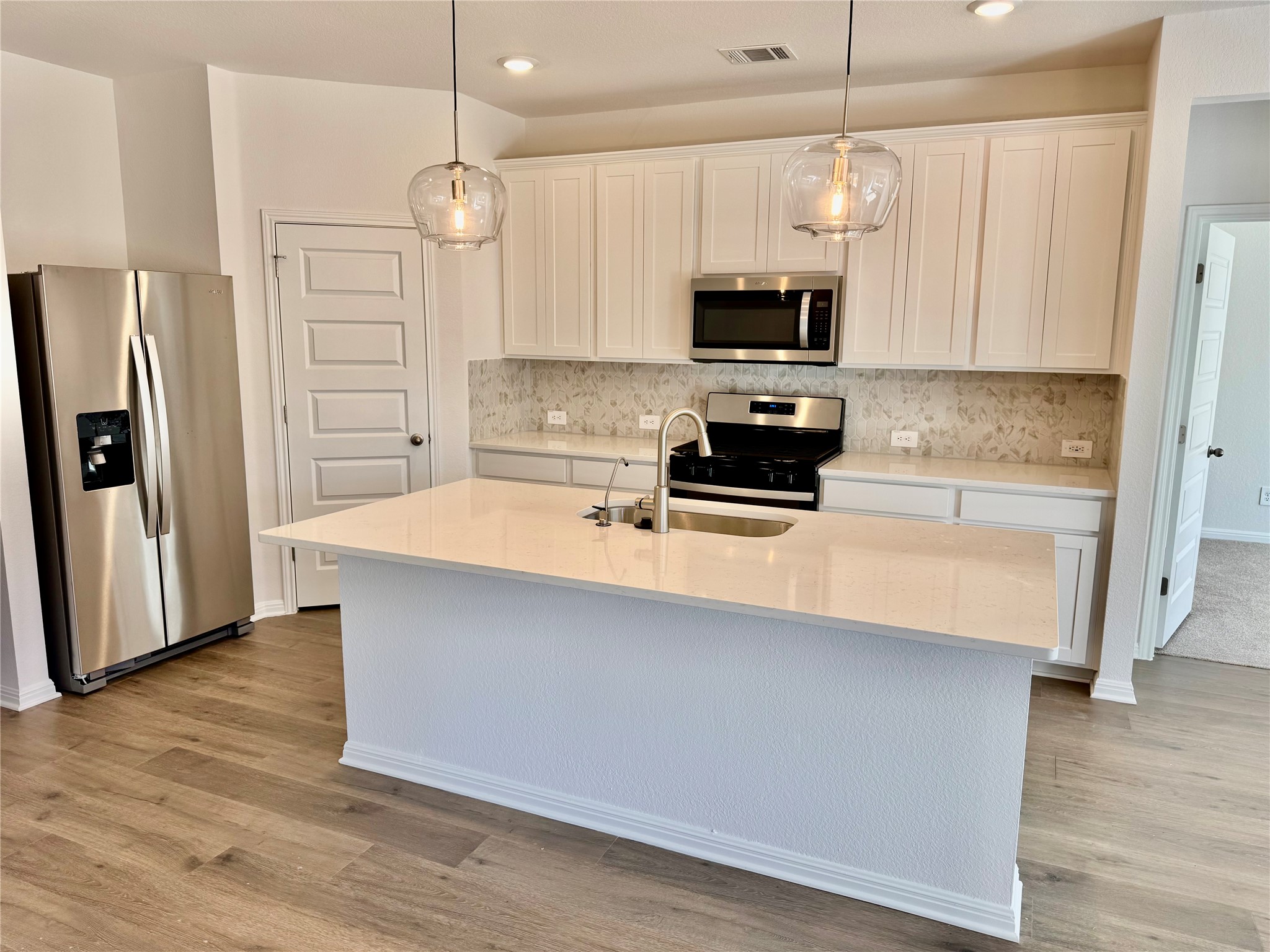 801 Sue Peaks Loop Dripping Springs, TX 78620 - Photo 2 of 18 a kitchen with stainless steel appliances a refrigerator a sink a stove a microwave and wooden floor