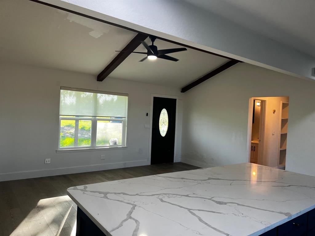 2025 County 1415 Road Bonham, TX 75418 - Photo 14 of 25 Vaulted ceiling with exposed beams and a ceiling fan, wood-finish flooring, white walls, and a front entry door with an oval glass insert