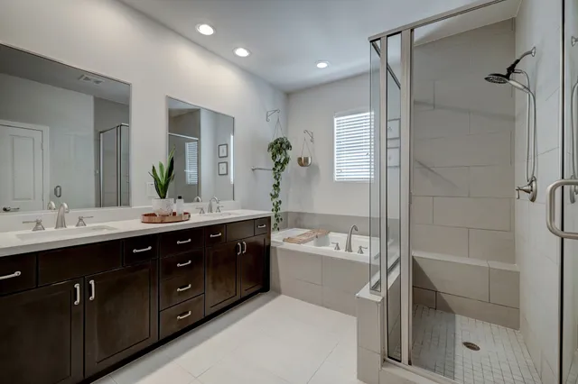 a spacious bathroom with a double vanity sink toilet mirror and bathtub