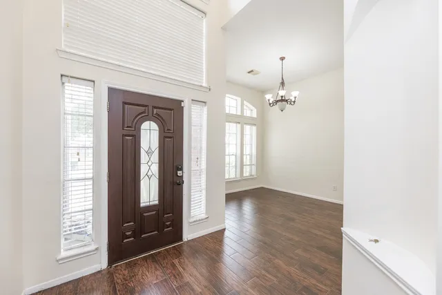 a view of a room with wooden floor chandelier and windows
