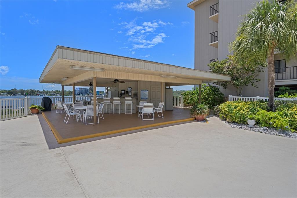 8211 Brent Street, Unit 836 Port Richey, FL 34668 - Photo 39 of 55 a view of a patio with a table and chairs under an umbrella with potted plants