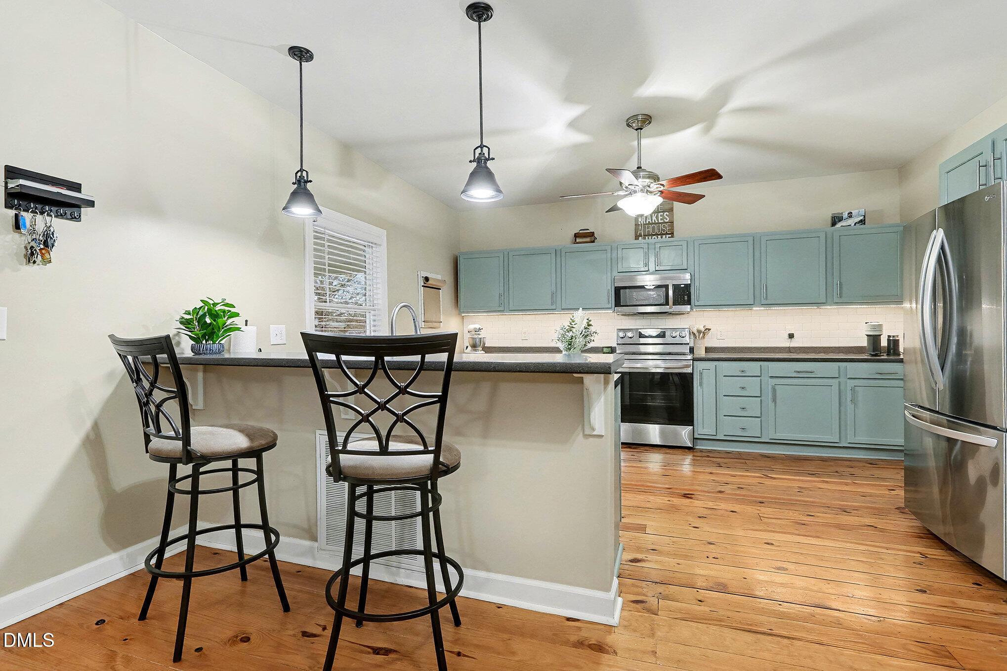 7228 Cleveland School Road Garner, NC 27529 - Photo 12 of 28 a kitchen with stainless steel appliances kitchen island a table chairs in it and wooden floors
