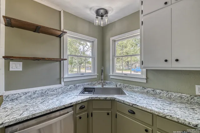a kitchen with granite countertop a sink window and cabinets
