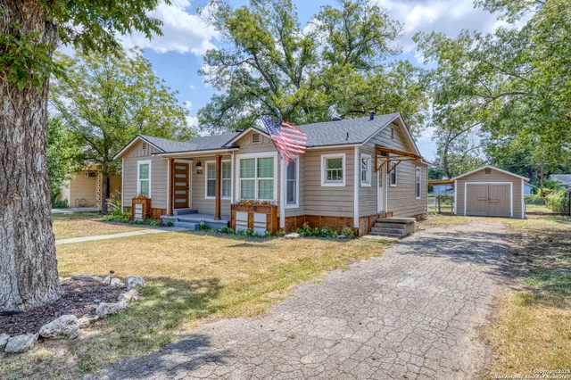 a view of a house with a yard and large tree