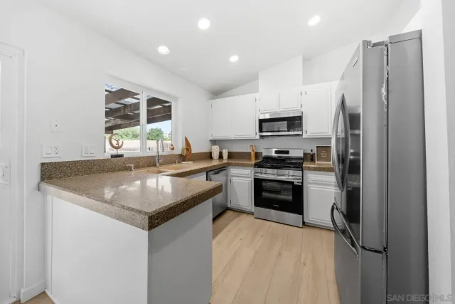 a kitchen with stainless steel appliances granite countertop a refrigerator a stove a sink and a microwave