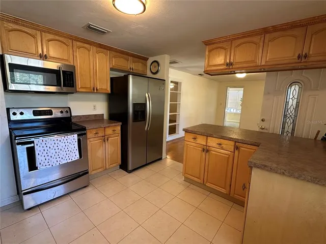 a kitchen with stainless steel appliances granite countertop a refrigerator a stove top oven and a sink