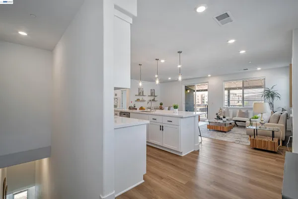 a living room with stainless steel appliances furniture and kitchen view