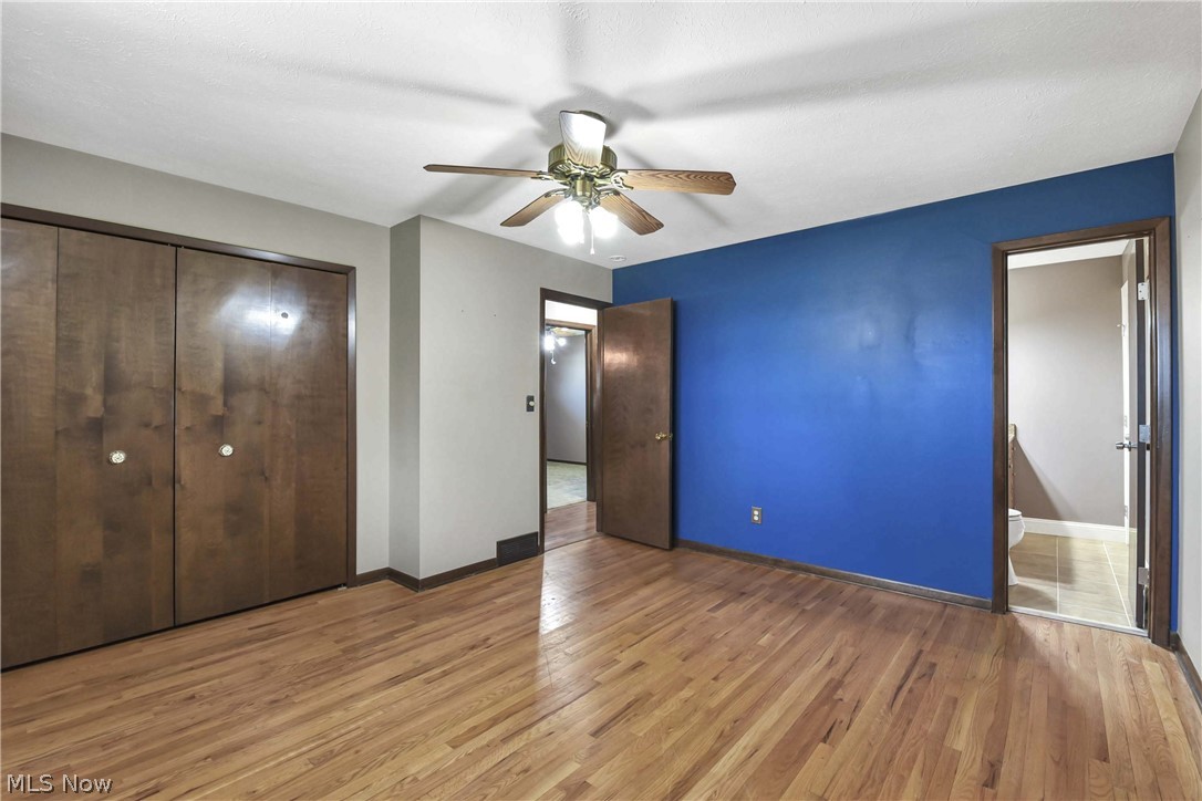7350 Ames Road Parma, OH 44130 - Photo 21 of 50 View of primary bedroom, bathroom access, closet doors, ceiling fan/light and blue accent wall