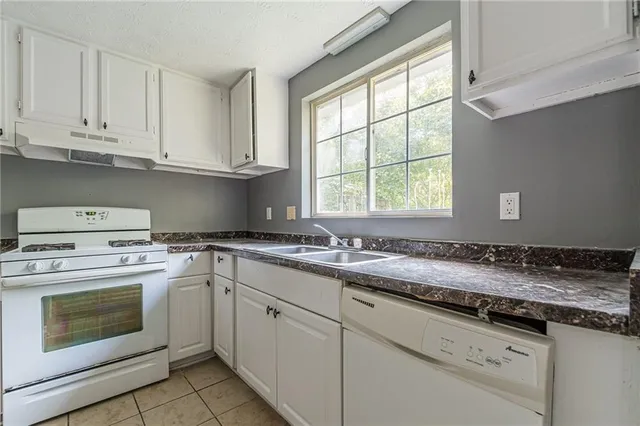 a kitchen with granite countertop white cabinets sink and window