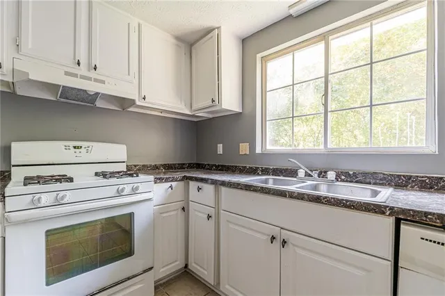 a kitchen with granite countertop white cabinets and white appliances