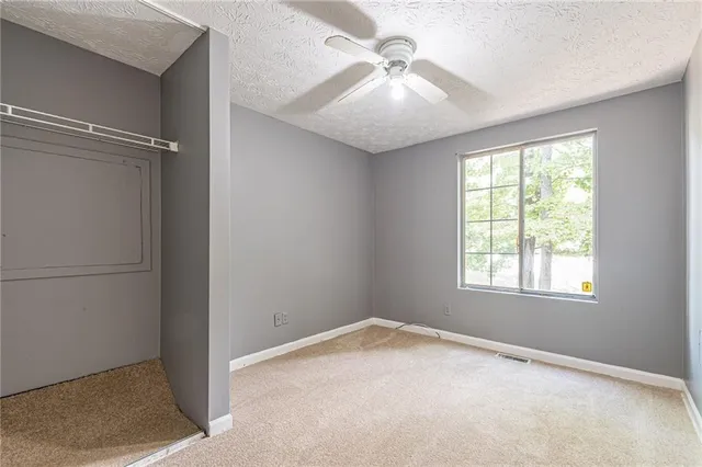 an empty room with a chandelier fan and windows