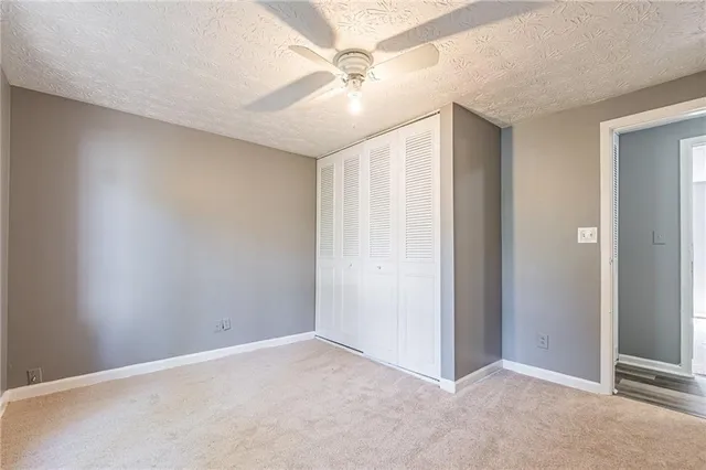 an empty room with closet and a ceiling fan