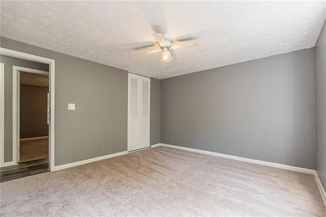 an empty room with closet and a ceiling fan