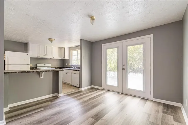a kitchen with granite countertop a refrigerator and wooden floor