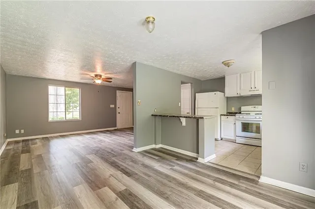 a view of a kitchen with wooden floor electronic appliances and windows