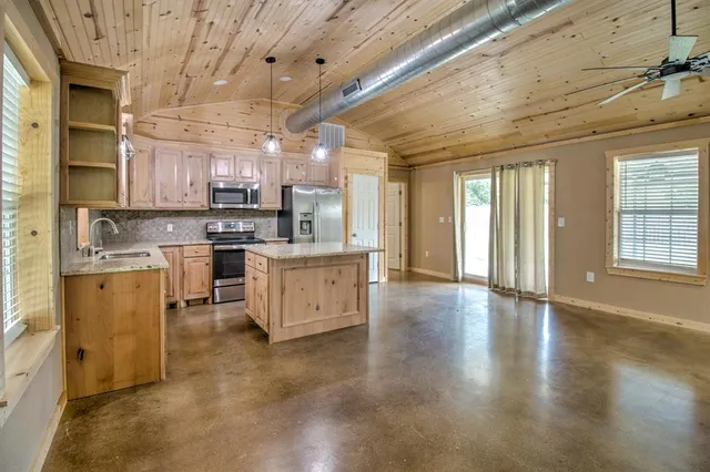 a kitchen with stainless steel appliances kitchen island granite countertop a stove top oven a sink a counter space and cabinets