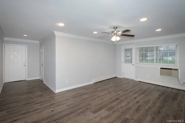 a view of an empty room with a window and wooden floor