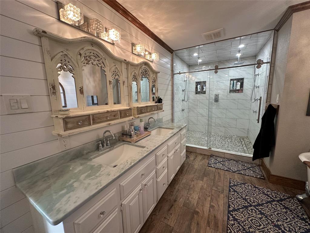 101 Twin Creek Road Comanche, TX 76442 - Photo 24 of 28 Bathroom with double vanity, dark wood finished floors, a shower stall, and crown molding