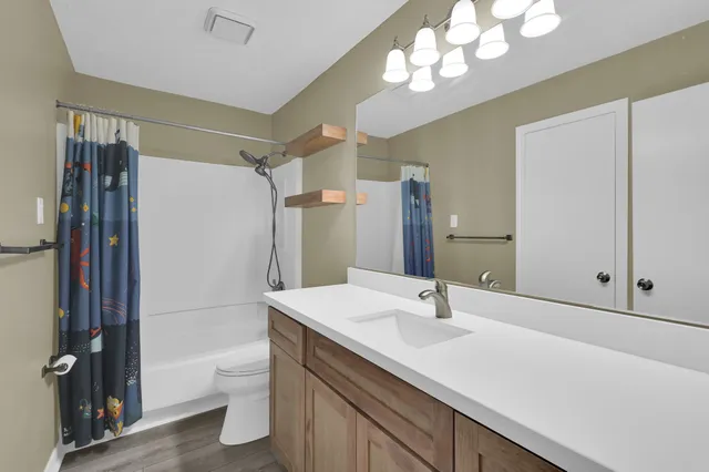 a bathroom with a sink a toilet a mirror and shower