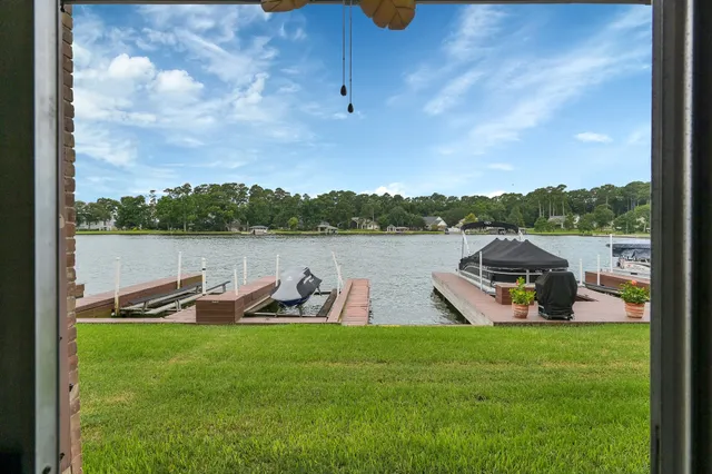 a view of a lake with a yard and a wooden fence