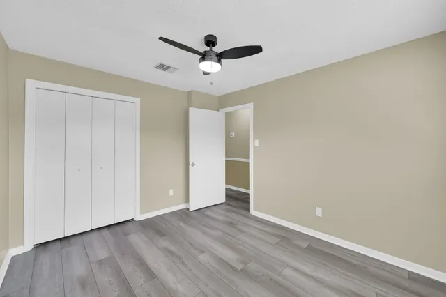 a view of empty room with wooden floor and ceiling fan
