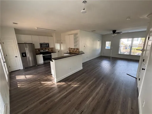 a kitchen with stainless steel appliances a refrigerator a sink dishwasher a stove top oven a wooden floor and a window